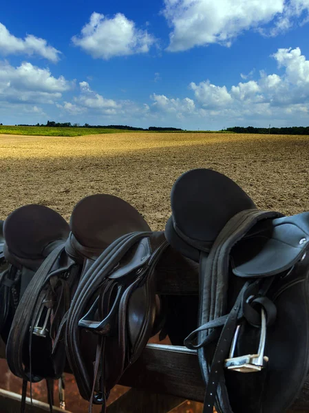 Leather Saddles on fence, agricultural land field plowing. — Stock Photo, Image