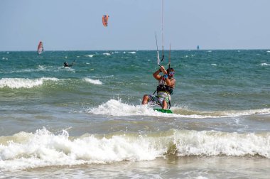 Eğitim uçurtması sörfçüsü dalgalarda sörf yapar. Deniz suyu sıçrar, cazibe kazanır.