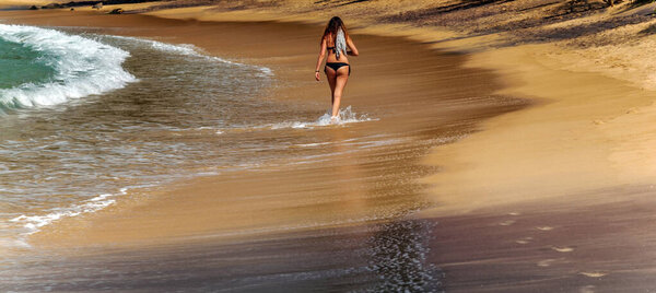 Summertime, Woman in a World Water Day Vulcan black sand beach in Iceland coast in the town of Mirissa, Sri Lanka