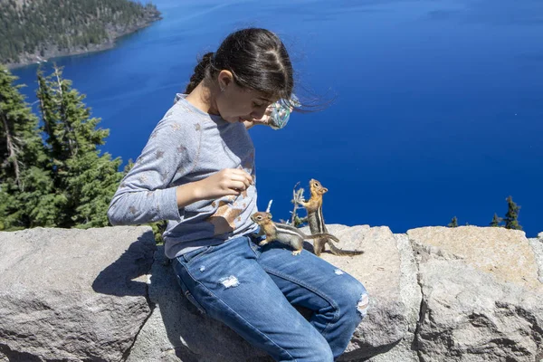 Meisje voedt een eekhoorn in Crater Lake National Park. Oregon. — Stockfoto