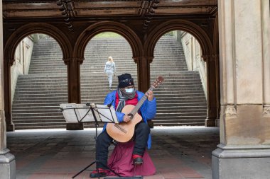 NEW YORK, NEW YORK - 17 Nisan 2020 'de New York' ta meydana gelen koronavirüs salgını sırasında Central Park 'ta koruyucu maske takan müzisyen.