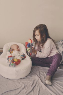 küçük kız yatak odasında yeni doğan kardeşi ile oynarken