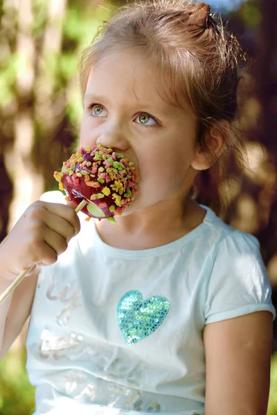 Niña comiendo manzana de caramelo — Foto de Stock