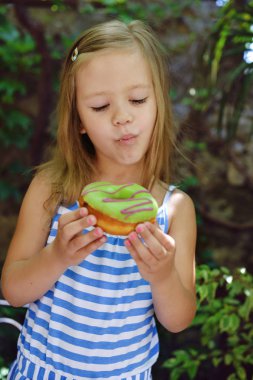 Sevimli küçük kız açık havada tatlı çörek yeme