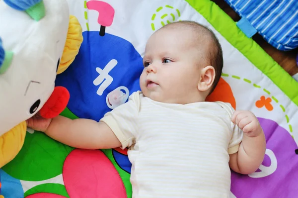 Baby op het speelgoed tapijt — Stockfoto
