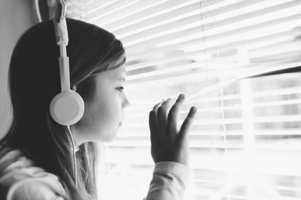 Trauriges Kleines Mädchen Schaut Aus Dem Fenster Durch Die Jalousie — Stockfoto