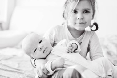 Sevimli küçük kız ve yeni doğmuş erkek bebek bir evde yatak odasında..