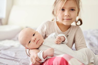 Sevimli küçük kız ve yeni doğmuş erkek bebek bir evde yatak odasında..