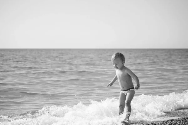 ビーチで波と遊ぶ幼児の男の子 — ストック写真