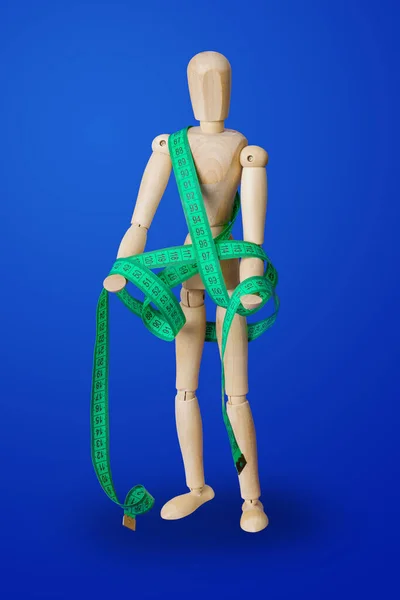 Figurine jouet en bois avec ruban à mesurer sur bleu — Photo