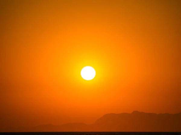 Orangefarbener Sommersonnenuntergang mit Bergsilhouette. — Stockfoto