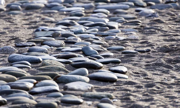 Stenen in zand aan de kust — Stockfoto