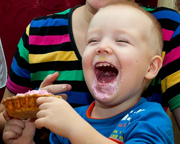 Menino comendo um bolo de xícara de creme fresco com rosto bagunçado — Fotografia de Stock