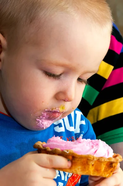 Niño pequeño comiendo un pastel de crema fresca taza con la cara desordenada — Foto de Stock