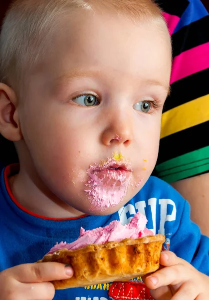 Menino comendo um bolo de xícara de creme fresco com rosto bagunçado — Fotografia de Stock