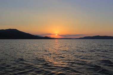 Deniz manzaralı, dağların üzerinde gün batımı