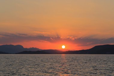 Deniz manzaralı, dağların üzerinde gün batımı