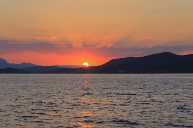 Deniz manzaralı, dağların üzerinde gün batımı