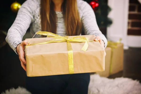 Mujer mantiene un regalo de papel en las manos —  Fotos de Stock