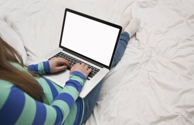 Genç kadın ile bir dizüstü bilgisayar yatağa yatıyor 