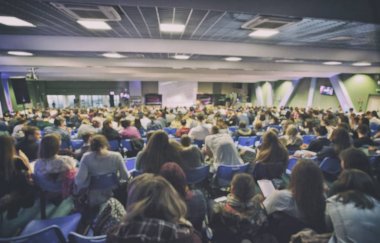 Bir sürü genç insan büyük bir salonda bir hoparlör dinleme