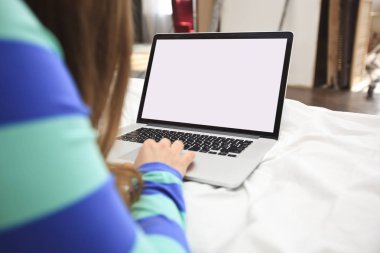 Genç kadın ile bir dizüstü bilgisayar yatağa yatıyor 