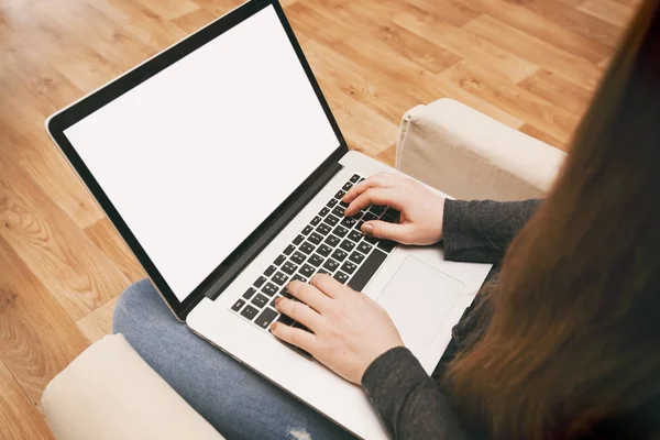 La giovane donna è seduta sul divano e lavora al computer portatile — Foto Stock