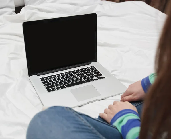 Die junge Frau liegt mit einem Laptop auf dem Bett — Stockfoto