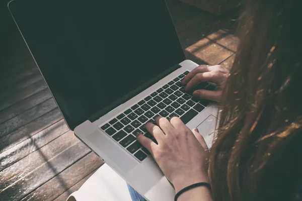 A jovem está sentada no chão e trabalhando no laptop — Fotografia de Stock