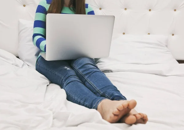 Die junge Frau liegt mit einem Laptop auf dem Bett — Stockfoto