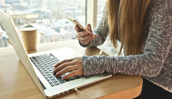 A jovem está sentada à mesa com laptop moderno e usa — Fotografia de Stock