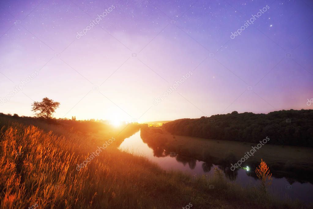 Beautiful dawn above the river and much of stars in the sky