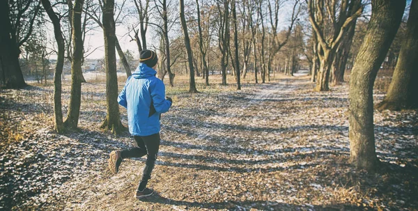 The young guy is jogging in the winter park — Stock Photo, Image