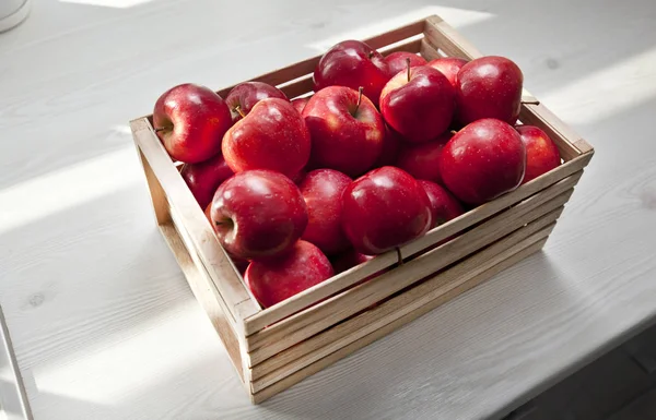 Mycket saftiga röda äpplen i trälådan på träbordet — Stockfoto