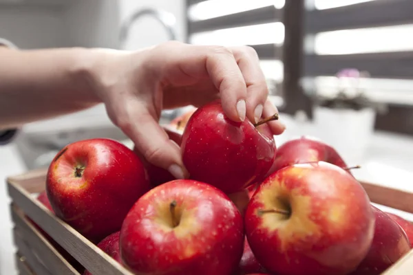 Kvinnan tar rött äpple från korg med frukt — Stockfoto