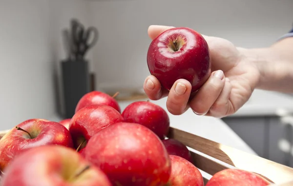 Kvinnan tar rött äpple från korg med frukt — Stockfoto