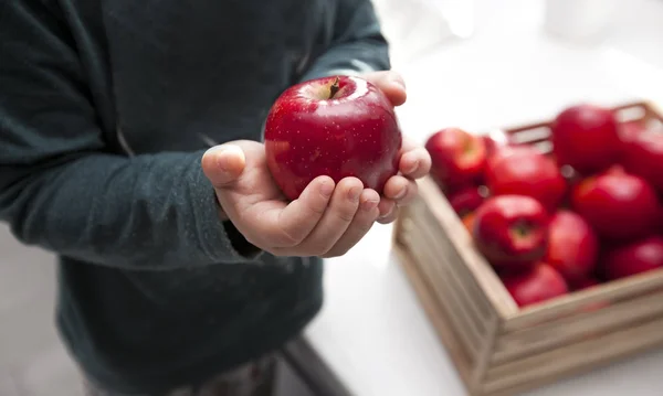 Barnet tar det saftiga röda äpplet från korgen med appen — Stockfoto
