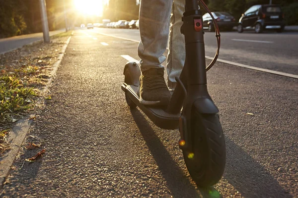 Młody człowiek jedzie na skuter elektryczny przez nawet — Zdjęcie stockowe
