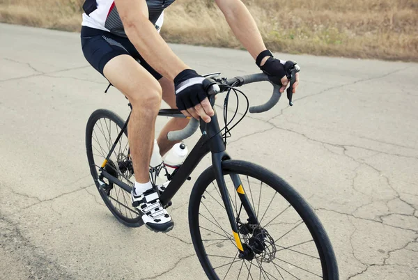 The cyclist is training on his road bike outside the city by asp — Stock Photo, Image