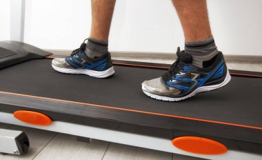 Koşu bandındaki spor ayakkabılı adamın bacakları.