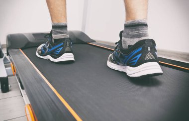 Koşu bandındaki spor ayakkabılı adamın bacakları.