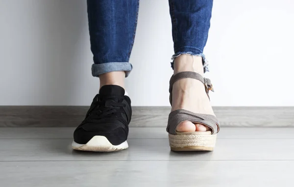 Dos tipos diferentes de zapatos en los pies de la mujer —  Fotos de Stock