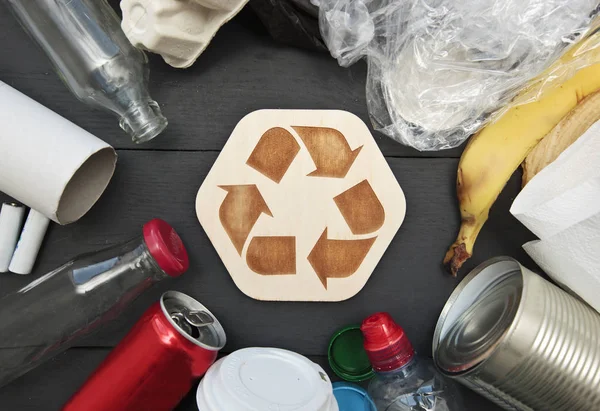 A lot of different garbage on the table and the recycling icon b