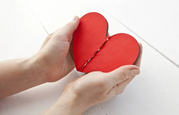 Η σπασμένη κόκκινη ξύλινη καρδιά στα χέρια της γυναίκας — Φωτογραφία Αρχείου