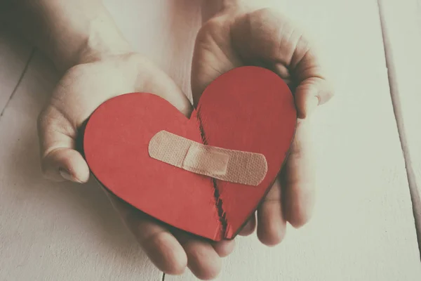 El corazón rojo roto de madera en las manos de la mujer —  Fotos de Stock