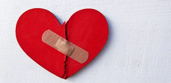 Дві частини червоного зламаного дерев'яного серця закріплені латкою. Концепція o — стокове фото