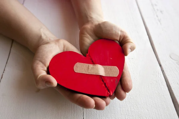 O coração de madeira vermelho partido nas mãos da mulher — Fotografia de Stock