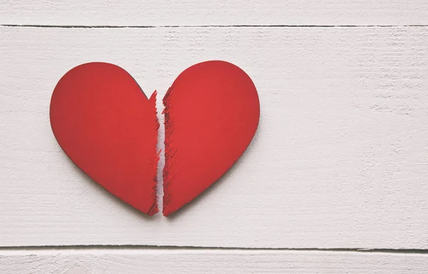 The broken red wooden heart on the wooden table. Concept of the — Stock Photo, Image