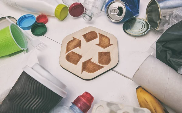 A lot of different garbage on the table and the recycling icon b — Stock Photo, Image