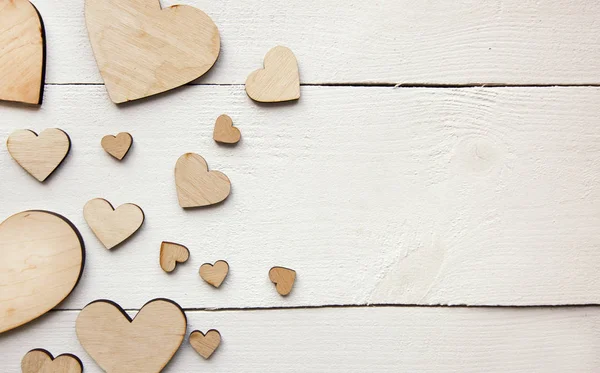 Un hermoso fondo con muchos corazones de madera en la t blanca — Foto de Stock